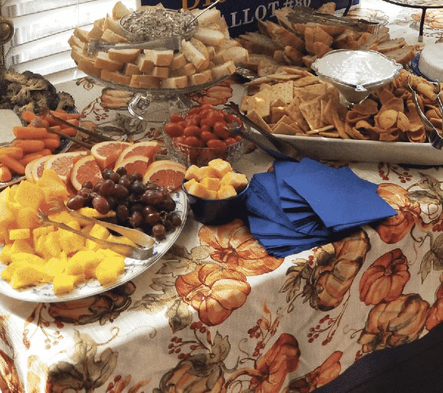 A festive table spread featuring various fruits, crackers, bread, and snacks.