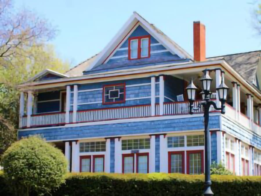 Victorian-style blue house with a red trim and a lamp post in front.